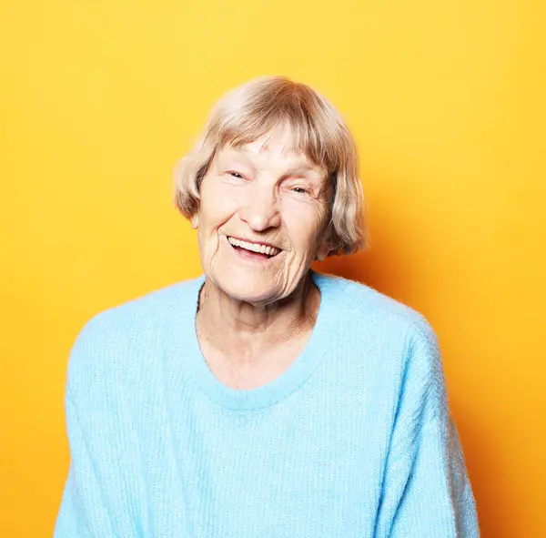 黄色の背景に微笑む美しい年上の女性の肖像画を閉じる — ストック写真