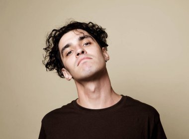 Mutlu gülümseyen adam bej arka planda kameraya bakıyor, yakın plan portre