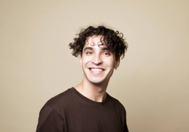 Mutlu gülümseyen adam bej arka planda kameraya bakıyor, yakın plan portre