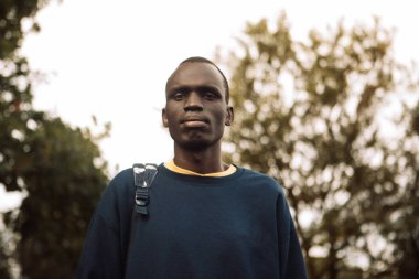 Genç bir siyah adam parkta yürüyor. Portreyi kapat. Yaz zamanı..