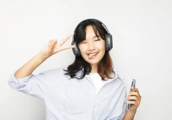 Neşeli Gülümseyen Asyalı Genç Kız Kulaklıkla Müzik Dinliyor Zafer Işareti Telifsiz Stok Fotoğraflar