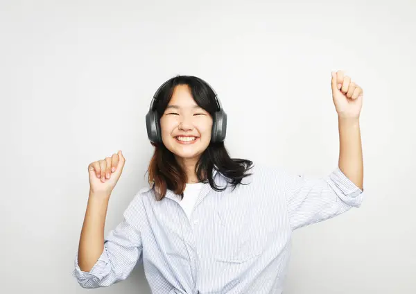 Hübsch Lächelndes Asiatisches Teenagermädchen Hört Musik Über Kopfhörer Vor Weißem Stockbild