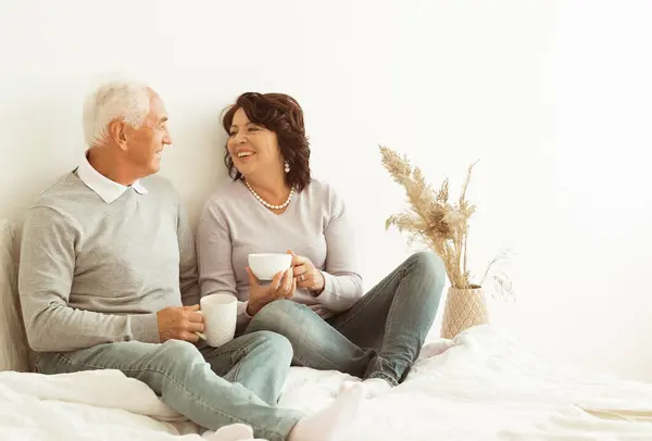 Glückliche Ältere 60Er Jahre Paar Kaffee Trinken Sitzen Auf Bett Stockfoto