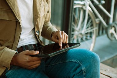 Genç yakışıklı bir adam akıllı telefon kullanır, sosyal ağlar, arkadaşlarıyla sohbet eder. Sokaktaki adam, bisikletin yanında oturuyor..