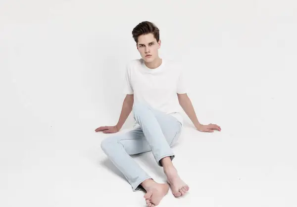 Joven Guapo Descalzo Modelo Masculino Jeans Una Camiseta Blanca Sienta Imágenes de stock libres de derechos