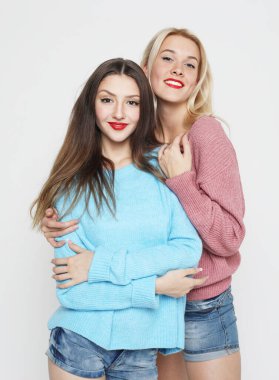 Beyaz gri arka planda izole edilmiş iki mutlu genç kadının stüdyo çekimi.