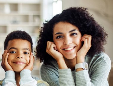 Close-up portrait of a dark-skinned young mother and a seven-year-old boy. A happy family at home.