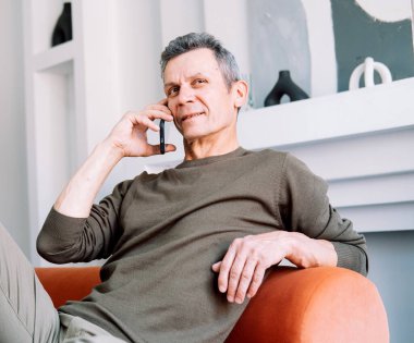 Serious concerned old man talking on mobile phone, calling for emergency, ambulance.