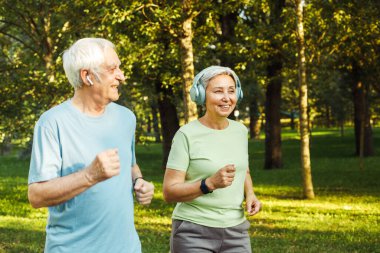 Gülümseyen yaşlı çift parkta koşuyor. Yaşam tarzı ve spor konsepti.