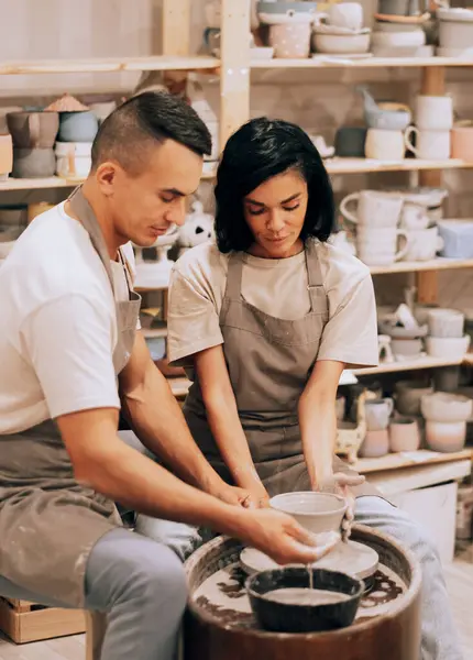 Stock image Couple in love working together on potter wheel in craft studio workshop.