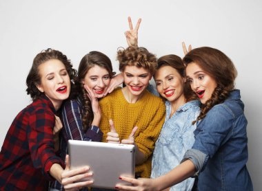 Beş hippi bayan arkadaş gri arkaplan üzerinde dijital tablet kullanıyor.