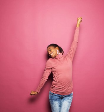 Güzel, genç, afro bir kadın dans ediyor.