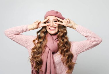 Gri arkaplanda barış işareti gösteren kıvırcık bir kadının portresi