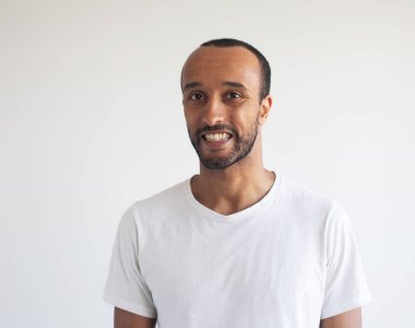 Genç afro adamın fotoğrafı gri arka planda beyaz tişört giyiyor.