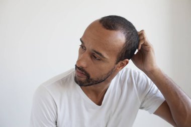 Açık gri arka planda traşsız genç bir adam..