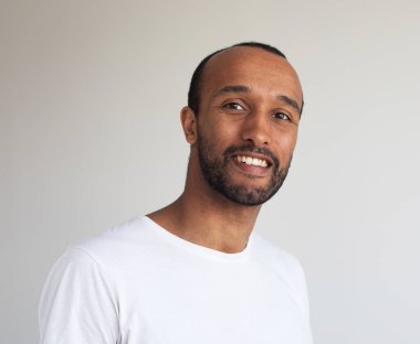 Genç afro adamın fotoğrafı gri arka planda beyaz tişört giyiyor.