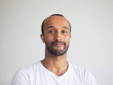 Genç afro adamın fotoğrafı gri arka planda beyaz tişört giyiyor.