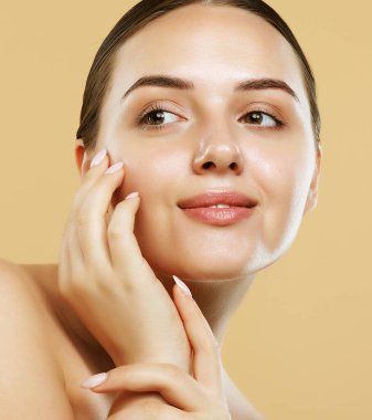 Beautiful Young Woman with Clean Fresh Skin look away. Portrait over beige background, close up. Cosmetology , beauty and spa concept.