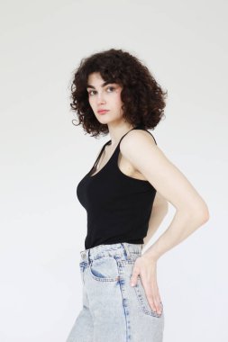 Siyah atletli şık kıvırcık kadın açık gri arka planda poz veriyor..