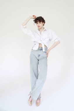 Beyaz arka planda poz veren kot ve beyaz gömlekli genç kıvırcık kadın model..