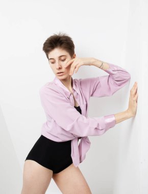 Kısa saçlı, pembe gömlekli, beyaz arka planda poz veren şık bir model..