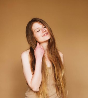 Bej arka planda izole edilmiş uzun saçlı güzel bir kadının stüdyo fotoğrafı..