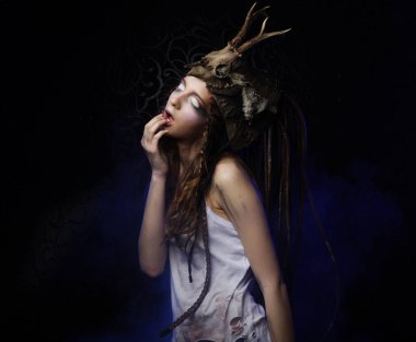 Parlak makyajlı, örgülü saçlı ve kafasında siyah bir arka planda poz veren güzel bir genç kadın. Karnaval partisi, Cadılar Bayramı konsepti.