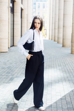 Siyah pantolonlu, beyaz pamuklu bluzlu, dışarıda poz veren şık bir kadın manken. Kadın modası. Şehir yaşam tarzı.