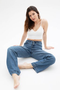 Stüdyoda beyaz arka planda poz veren uzun siyah kıvırcık saçlı model.