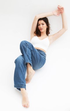 Stüdyoda beyaz arka planda poz veren uzun siyah kıvırcık saçlı model.