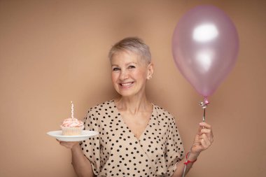 Elinde mumları ve balonları olan güzel, yaşlı bir kadın..