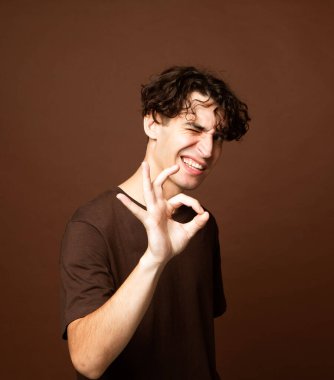 Kahverengi arka planda gülümseyen genç adam, yaşam tarzı konsepti.