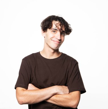 Kahverengi tişört giyen mutlu adam kameraya bakıyor çapraz kollu, beyaz arka planda, yakın çekim