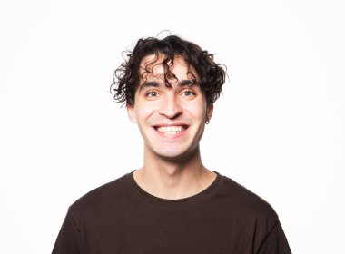 Kahverengi tişört giyen mutlu bir adam beyaz arka planda kameraya bakıyor.