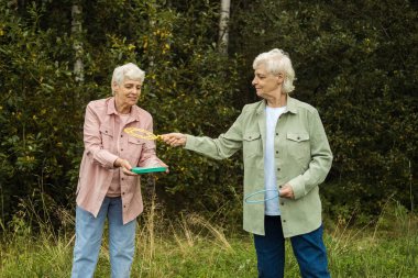 Bir yaz parkında sabun köpüğü üfleyen iki yaşlı kız kardeş, yaşam tarzı konsepti..