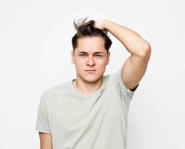 Genç bir adam düşünceli bir şekilde kafasına dokunur, bir şey düşünür.