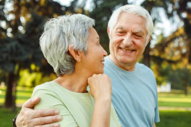 Parkta yaz yürüyüşüne çıkmış yaşlı bir çift. Çokuluslu evlilik. Yakın plan portreler. Yaşam tarzı kavramı.