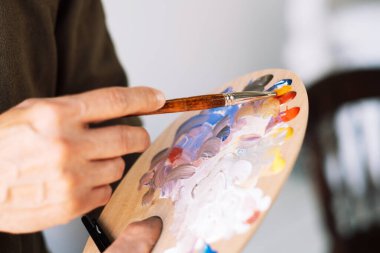 Erkek ellerinin fırça ve palet tutuşu. Sanatçı yaratmaya hazır. Sanat ve insan konsepti.