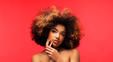 Kırmızı arka planda güzel bir makyajı olan genç Afrikalı kadın modelin portresi. Portreyi kapat.