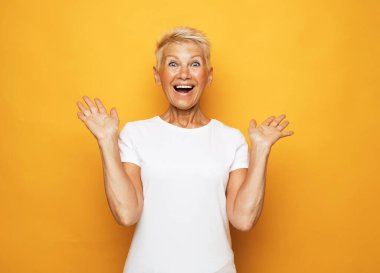 Sarı arka planda yaşlı, şaşırmış kadın, duygusal portre..