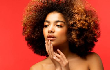 Kırmızı arka planda güzel bir makyajı olan genç Afrikalı bir modelin portresi. Kapat..