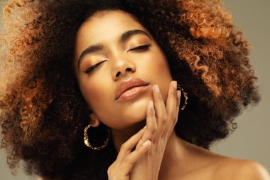 Bej arka planda, şehvetli, kıvırcık Afrikalı bir kadının portresi. Güzellik, insanlar ve moda konsepti.