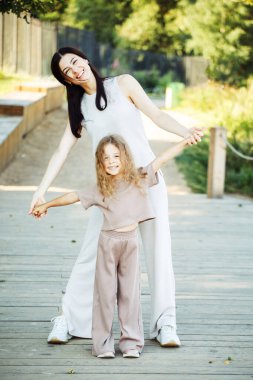 Genç bir esmer anne ve altı yaşındaki kızı bir yaz parkında dans edip eğleniyorlar..