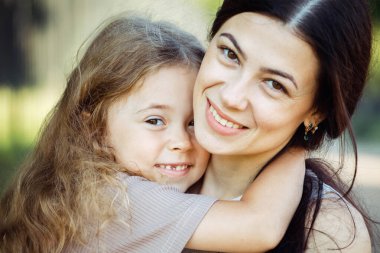 Mutlu yaz zamanları. Küçük kızı parkta genç ve mutlu annesine sarılıyor. Yaşam tarzı kavramı.