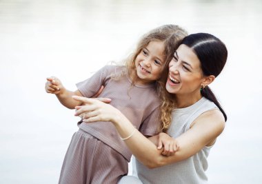 Genç bir anne ve beş yaşındaki kızı göl kenarındaki iskelede duruyorlar ve suya bakıyorlar. Aile hayatı.