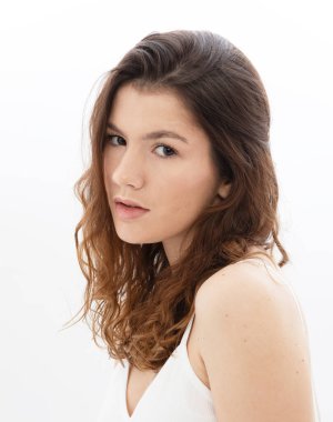 Stüdyoda beyaz arka planda poz veren uzun siyah kıvırcık saçlı bir model portresi.