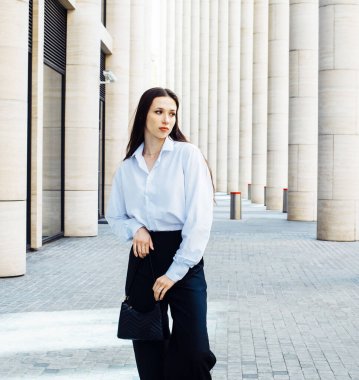 Uzun saçlı genç bayan model beyaz gömlek ve siyah boya giyer..