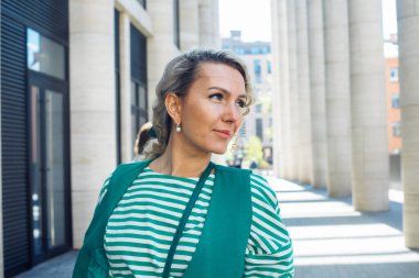 Şık kıvırcık bir sarışın yaz şehrinin sokaklarında yürüyor..