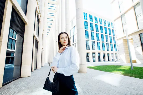 Siyah pantolonlu, beyaz pamuklu bluzlu, dışarıda poz veren şık bir kadın manken. Kadın modası. Şehir yaşam tarzı.