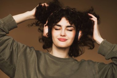 Yaşam tarzı ve insan konsepti: kulaklıklı genç bir kadın müzik dinliyor, gülümsüyor ve dans ediyor..